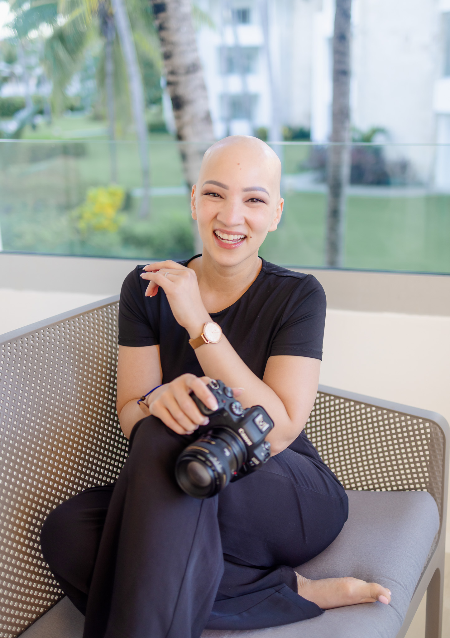 Photo of a smiling bald woman holding a camera in a casual pose